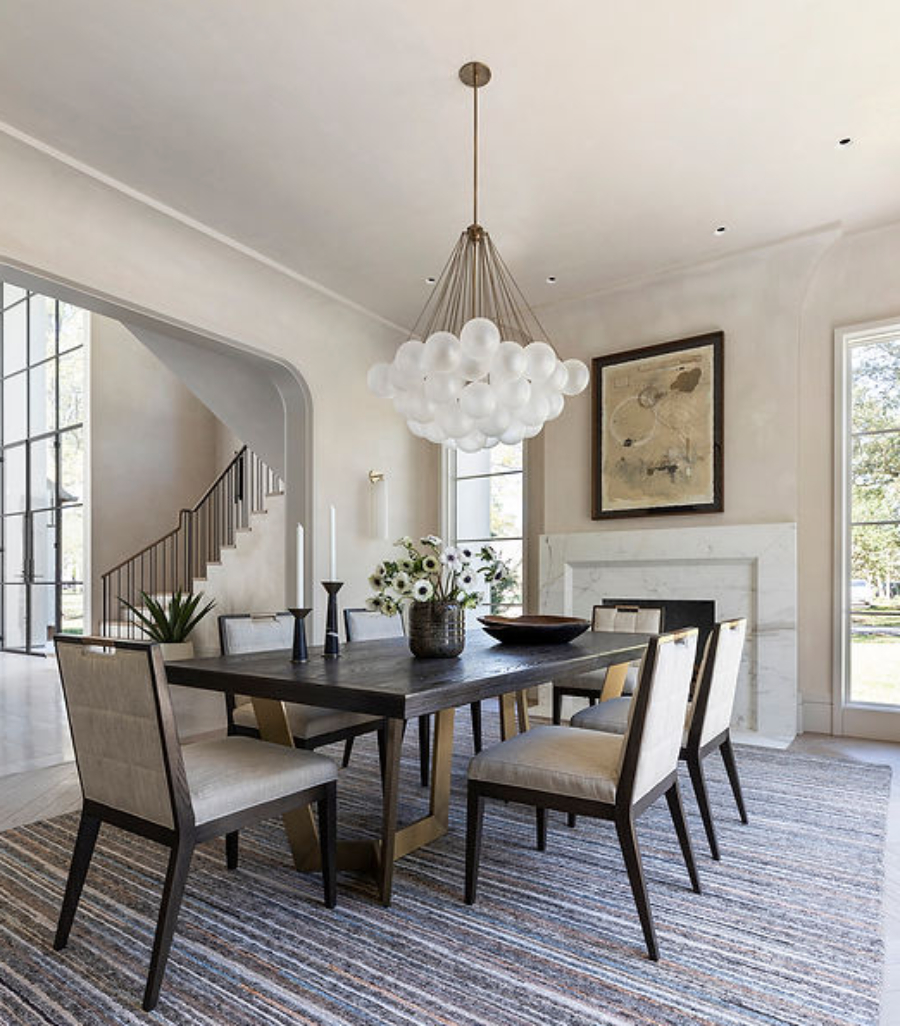 Benjamin Johnston Design: Dining And Living Room Inspiration. A dining area with a striped rug, a dining table with six dining chairs, and a suspension light looking like white bubbles.